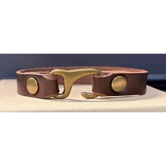 Brown leather bracelet with brass fastener on a neutral background