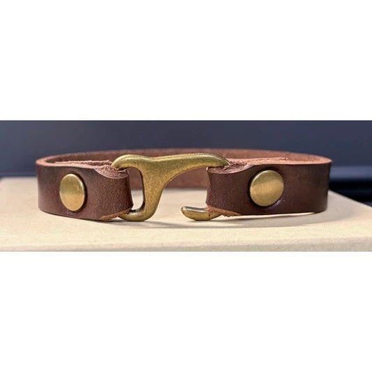 Brown leather bracelet with brass fastener on a neutral background