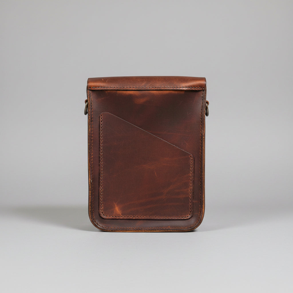 A brown leather crossbody bag with a flap closure and adjustable strap.