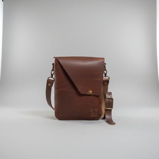A brown leather crossbody bag with a flap closure and adjustable strap.