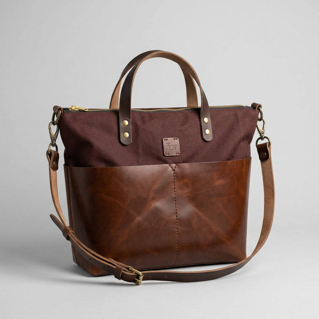 A brown and burgundy two-tone tote bag with a top handle, zipper closure, and adjustable shoulder strap.